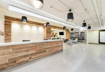 Bright reception area featuring a long wood-paneled desk and industrial-style lighting.