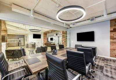 Professional meeting room with a large wooden table, black leather chairs, and a glass wall.