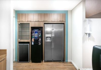 Communal kitchen area with a stainless steel refrigerator and light wood cabinetry.