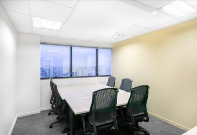 Private office space with a white desk and black mesh chairs near a large window.
