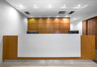 Modern reception desk with a white front and warm wood paneling backdrop.