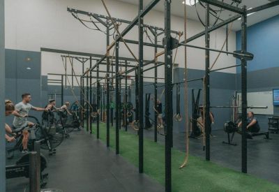 Modern gym facility with a green turf strip and weightlifting racks.