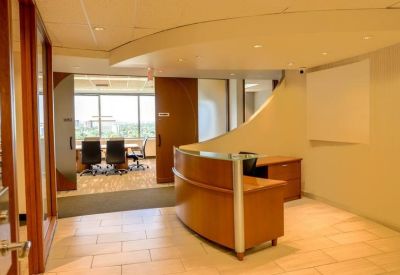 Professional reception area with a curved wooden desk and soft recessed lighting.
