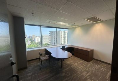 Private office with a curved wooden desk and large windows overlooking the city.