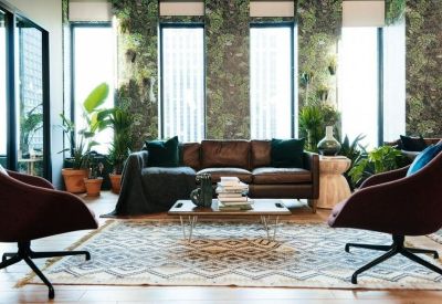 Bright lounge area with a leather sofa, patterned rug, and floor-to-ceiling windows.