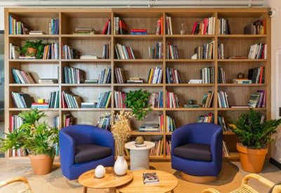 Cozy lounge area with blue armchairs in front of a floor-to-ceiling bookshelf.