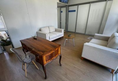 Private office space with a classic wooden desk, cream sofas, and large glass partitions.