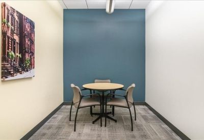 Small meeting room with a round table, four chairs, and a blue accent wall.