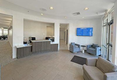 Sleek modern reception area with wood-paneled desk and blue lounge chairs.