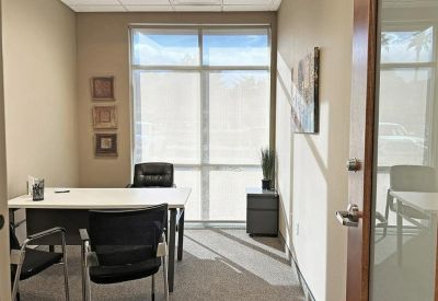 Private internal office featuring a white desk, black chairs, and framed wall art.
