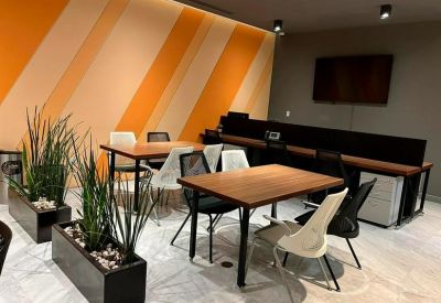 Modern communal area featuring orange striped walls, wooden tables, and indoor plants.