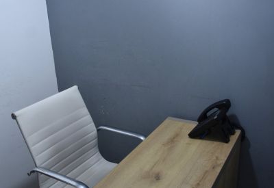 Private internal office with a light wood desk, white leather chair, and a black telephone.