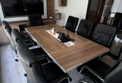 Meeting room featuring a long wooden conference table, black leather chairs, and large display screen.