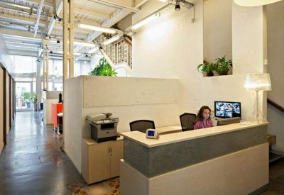 Professional reception area with a grey and white desk and indoor plants.