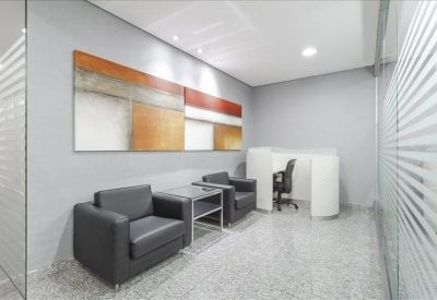 Waiting area with sleek black armchairs, glass side tables, and colorful abstract wall art.