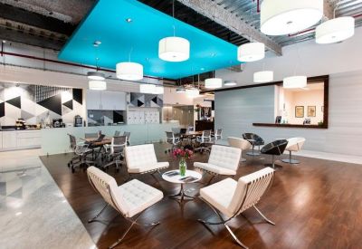 Colorful breakout lounge with a bright blue ceiling feature and white designer armchairs.