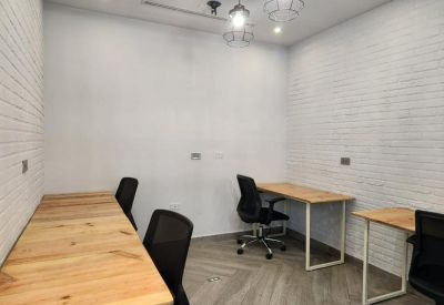 Shared office suite with white faux-brick walls and three light wood desks.