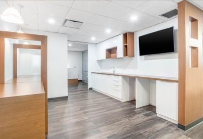Modern breakroom area with wooden accents, white cabinetry, and a wall-mounted TV.