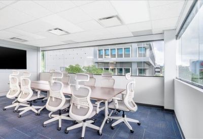 Professional meeting room with a large table, white mesh chairs, and window views.