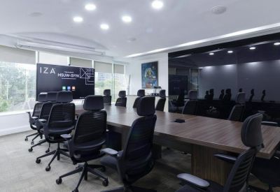 Spacious boardroom with a large wooden table and modern black ergonomic chairs.