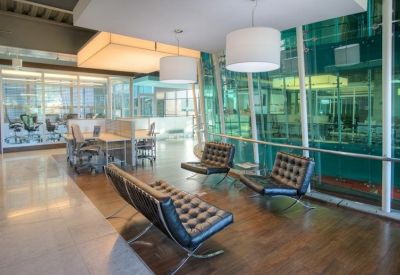 Bright coworking area with white tufted benches and green glass partitions.