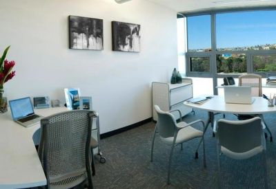 Modern private office with white desks, mesh chairs, and framed artwork.