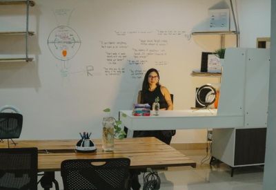 Reception area featuring a white desk, whiteboard with diagrams, and a seated staff member.