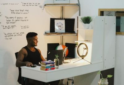 Individual workstation with a white desk, ring light, and handwritten notes on the wall.