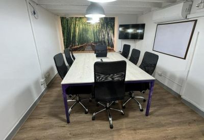 Conference room with a large white table, black chairs, and a forest mural.