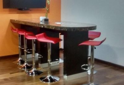 Employee breakroom featuring a high-top dark wood counter, red bar stools, and a wall-mounted TV.