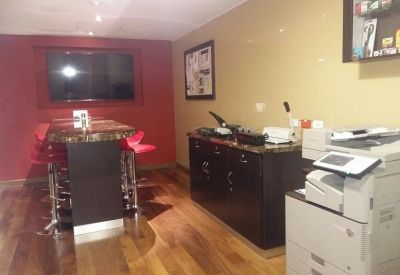 Office utility area with a high-top work table, red stools, and a large professional copy machine.