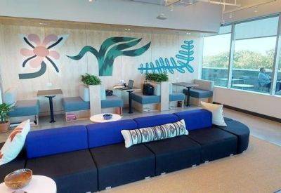 Modern breakout area featuring a blue sofa and vibrant wall mural.