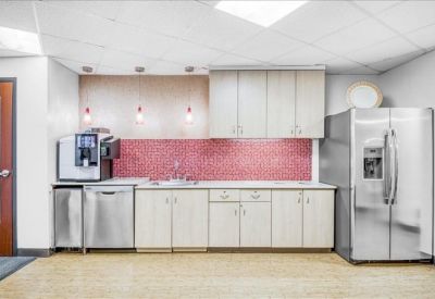 Communal kitchen area featuring a pink tile backsplash and stainless steel appliances.
