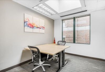 Bright corner office with a light wood desk and colorful wall art.
