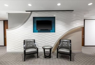 Modern lounge area featuring textured white walls and stylish grey armchairs.