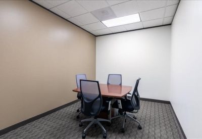 Small meeting room with a wooden table and four mesh chairs.