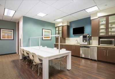Bright communal kitchen and breakout area with a long white table.