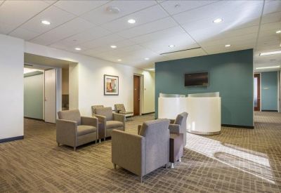Spacious reception lounge with comfortable grey armchairs and a blue accent wall.