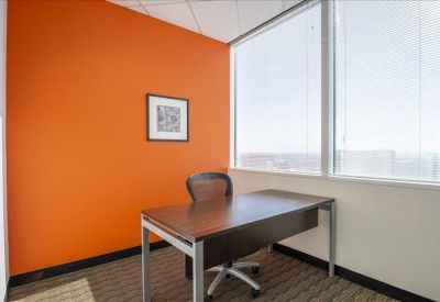 Private office featuring an orange accent wall and large window.