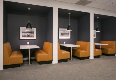 Semi-private meeting booths with orange leather seating and dark accent walls.