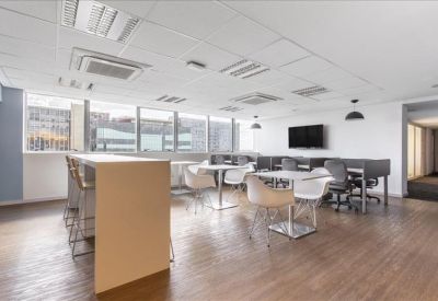 Communal breakout area with high tables, stools, and a television mounted on a white wall.