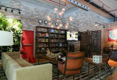 Industrial-style lounge with brick walls, bookshelves, and a green plant wall.