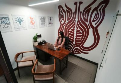 Private office featuring a dark wood desk and a large red patterned wall mural.