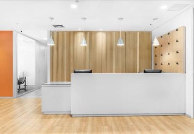 Sleek white reception desk with warm wood paneling and stylish pendant lights.