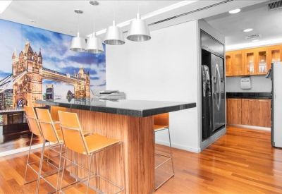 Modern breakroom with wood floors, high-top seating, and London bridge mural.