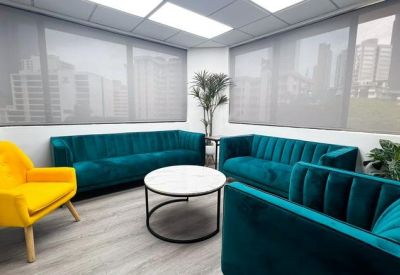 Spacious communal lounge featuring teal velvet sofas and a vibrant yellow armchair.