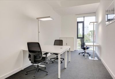 Private office featuring two white desks and black ergonomic chairs.