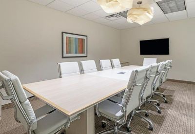 Spacious boardroom with a long white table and modern pendant lighting.