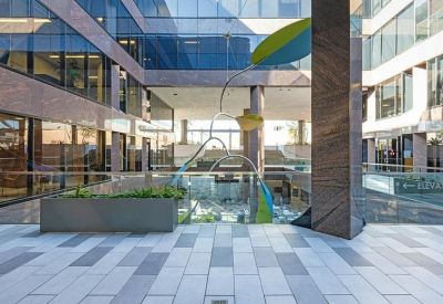 Exterior courtyard of Camelback Commons with a modern glass facade and sculptural art piece.