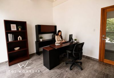Single occupant private office suite with dark wood desk and matching bookshelf.